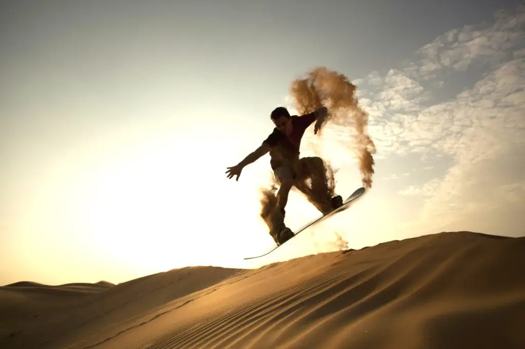 Guy doing jump while sandboarding.