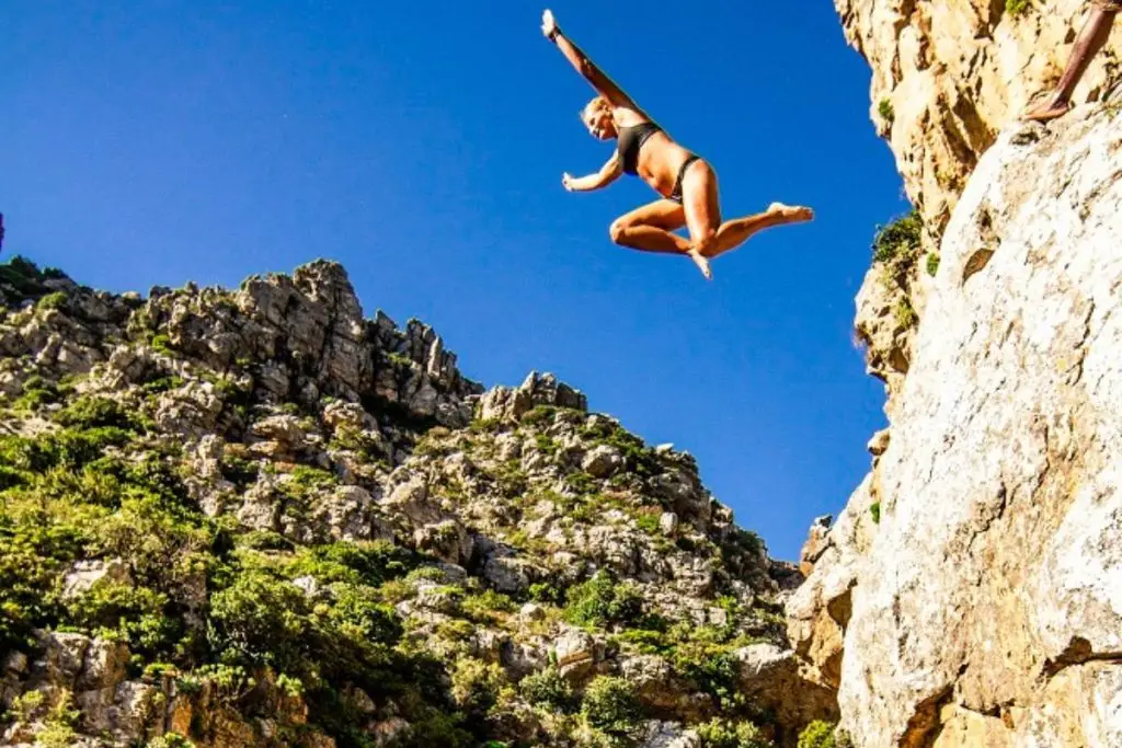 Bottom view of girl jumping into rock pool.