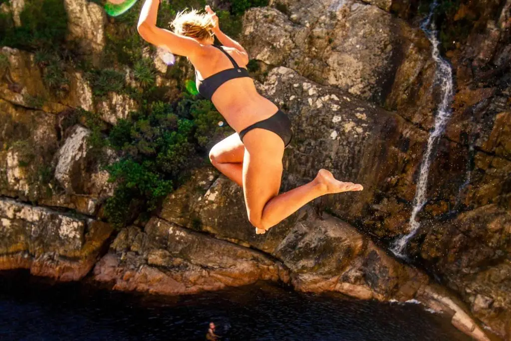 Top view of girl jumping into rock pool.